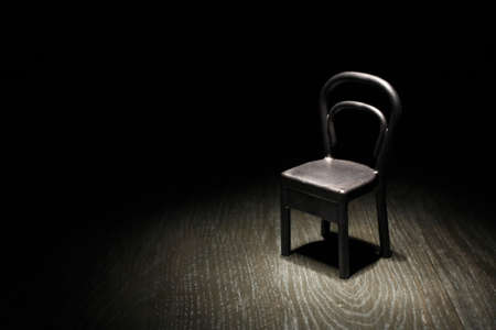 An Empty black chair in dark room under beam of lightの写真素材
