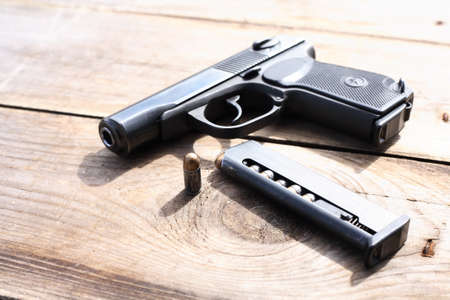 Eight-capacity magazine near handgun on wooden background