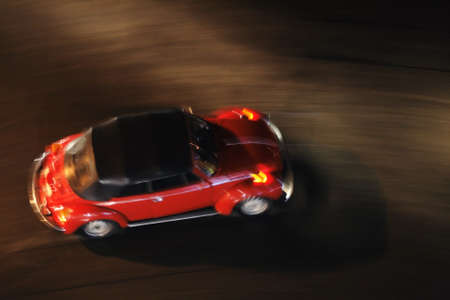 A red car is moving at night at high speed