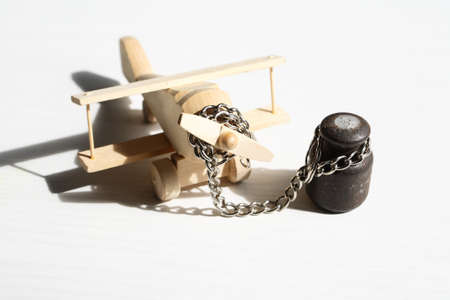 Flight ban concept. Small wooden airplane attached with metal chainの写真素材
