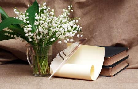 Still life with open book and quill pen near posy of white liliesの写真素材