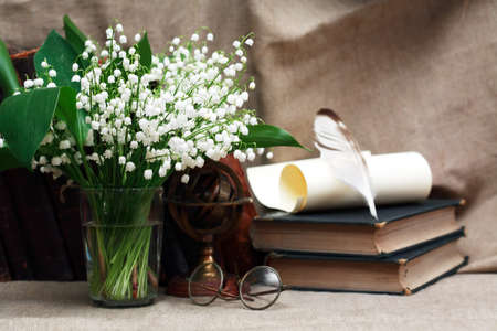 Still life with open book and quill pen near posy of white liliesの写真素材