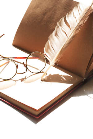 Still life with open book and quill pen under sun lightの写真素材
