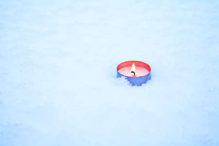 One lighting candle on snow surface with free spaceの写真素材