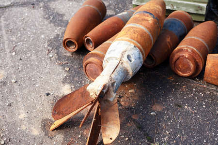 Waste of war. Few rusty used missiles on gray asphalt backgroundの写真素材
