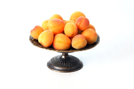 Heap of freshness apricots in vintage bowl on white backgroundの写真素材