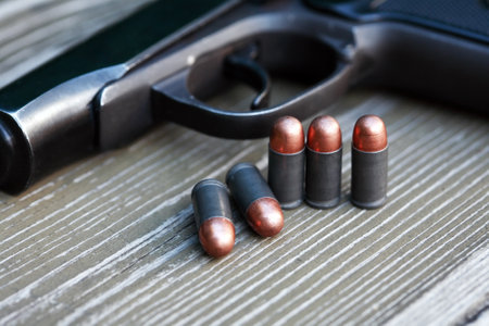 Handgun cartridges closeup on old wooden background near pistolの写真素材