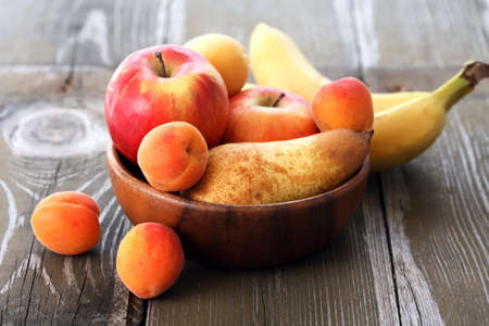 Heap of freshness fruits in bowl on old wooden tableの写真素材