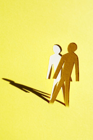 Man figure cutting from yellow paper with long shadowの写真素材