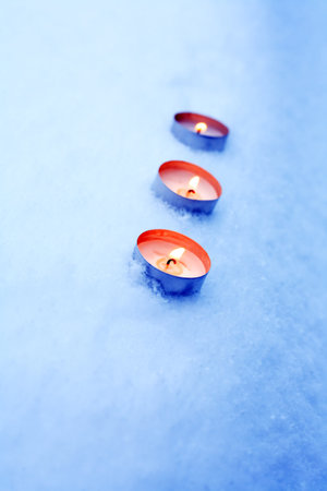 Few lighting candles on snow surface with free spaceの写真素材