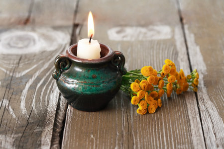 One lighting candle near bunch of yellow wild flowersの写真素材