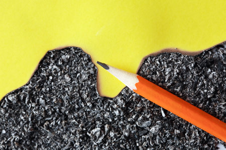 Burnt yellow paper and pencil on gray ash background