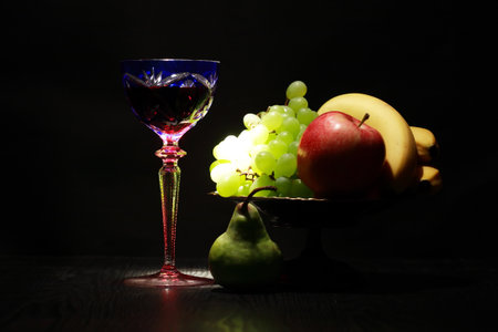 Still life with nice vintage wine glass near fruits on dark backgroundの写真素材