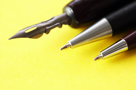 Three various pens closeup on yellow paper backgroundの写真素材