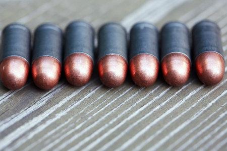 Closeup of few pistol bullets in a row on old wooden backgroundの写真素材