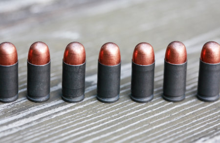 Closeup of few pistol bullets in a row on old wooden backgroundの写真素材