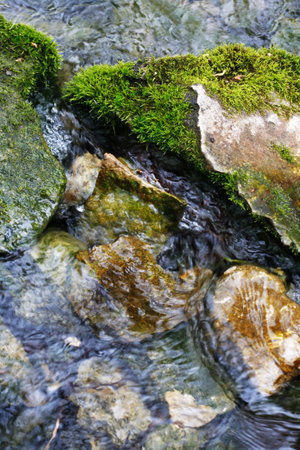 nature background. Closeup of few rocks with green moss in the streamの写真素材