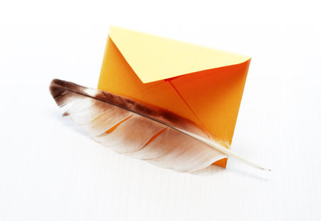 Retro message. Quill pen near yellow envelope on white backgroundの写真素材
