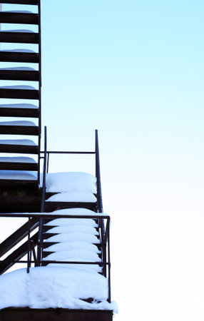 Stairway to heaven. Closeup of fire escape with snow against winter skyの写真素材