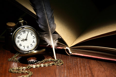 Nice vintage still life with pocket watch and feather near old bookの写真素材