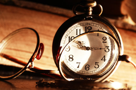 Old eyeglasses and pocket watch on background with books
