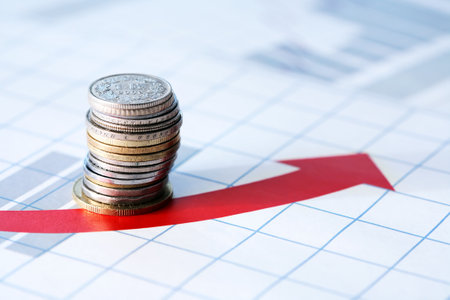 Business concept. Column of coins on diagram background with red arrowの写真素材