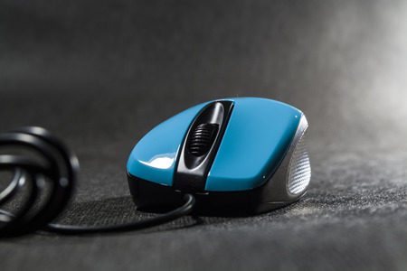 Computer mouse of bright blue color. Black details. Plastic. Modern technologies. Black background.の写真素材