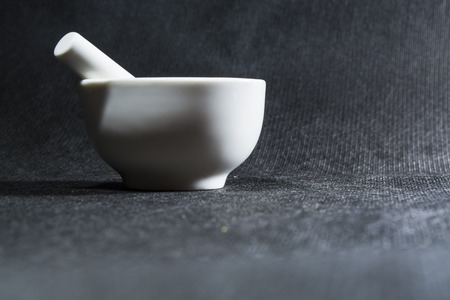 White mortar with a pestle from porcelain. A drinking bowl for crushing of spices. Black background. Kitchen utensils.の写真素材