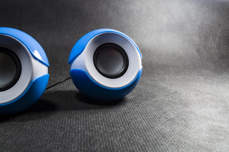 Small and portable round speakers for reproduction of music. Modern technologies. Electronics. Black background. White. Blue.の写真素材