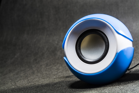 Small and portable round speakers for reproduction of music. Modern technologies. Electronics. Black background. White. Blue.の写真素材