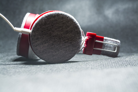 Big and white earphones for listening of music. Red plastic and skin. On a black background. Modern technologies.の写真素材