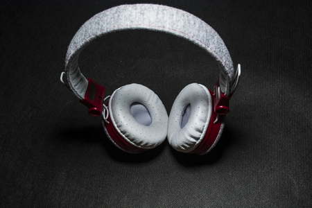 Big and white earphones for listening of music. Red plastic and skin. On a black background. Modern technologies.の写真素材