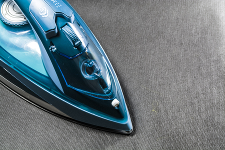 The blue iron for ironing of clothes. Monophonic black background. Household appliances. Electronics.の写真素材