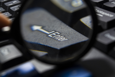 Black computer keyboard. The button an enter under a magnifying glass. Lens. Modern equipment. Computer.の写真素材