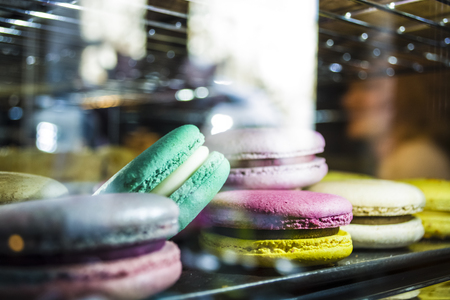 Glass show-window with illumination in coffee shop with multi-colored French macarons. Tasty sweets.の写真素材