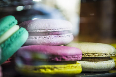 Glass show-window with illumination in coffee shop with multi-colored French macarons. Tasty sweets.