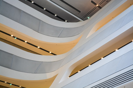 Modern unusual building inside. With white slanted and semicircular walls, big windows and balconies, with illumination. Architecture of lines. Geometry.の写真素材