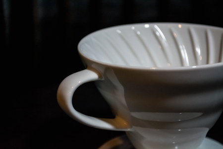 White funnel Pourover on a black background for preparation of coffee by an alternative method. Work the barista in coffee shop. Strong drink with caffeine.の写真素材