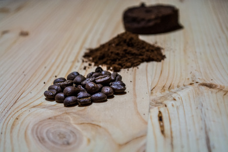 Three stages for preparation of coffee: grain, crushing and the pressed tablet. Wooden surface. Espresso.の写真素材