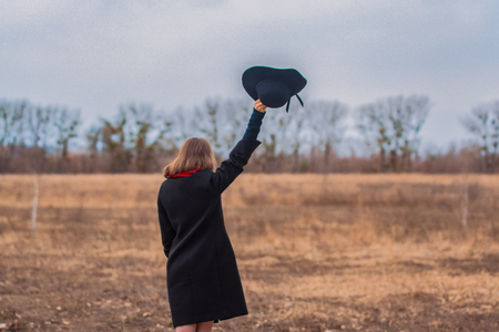 The girl in a black coat, a shovel hat and with red lipstick on lips, walks in the park. Style and modern fashionの写真素材