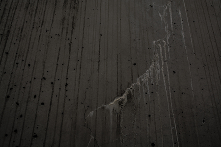Gray monophonic background with textural holes in a concrete wall with cracks and dripsの写真素材