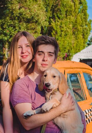 The young married loving couple walks with the little dog in the park. Golden retrieverの写真素材