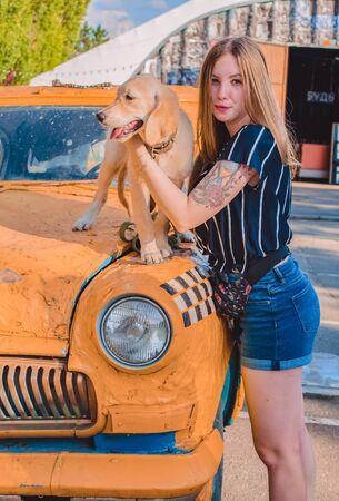 The young woman walks with the little dog in the park. Golden retrieverの写真素材
