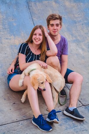 The young married loving couple walks with the little dog in the park. Golden retrieverの写真素材