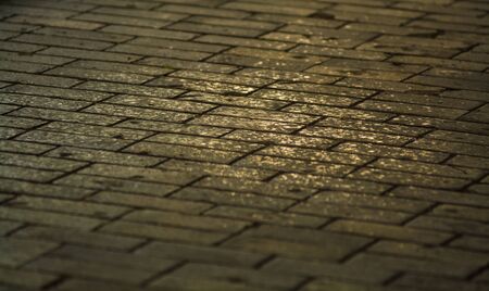 Background or texture from a broken and equal tile with patches of light and drops. Stone blocks on the sidewalkの写真素材