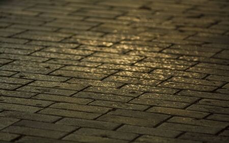 Background or texture from a broken and equal tile with patches of light and drops. Stone blocks on the sidewalkの写真素材