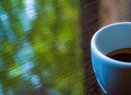 White ceramic cup from espresso on glossy brown surface. Coffee and good morning. Background
