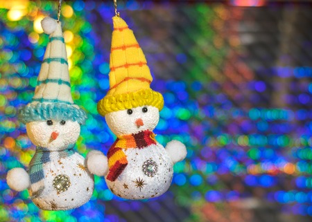 Two toy snowman on the background of colorful bokeh. Meeting Christmas and New Year.の写真素材