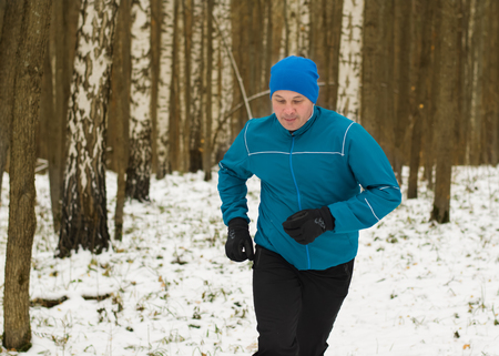 The man likes to run in the winter forest. Healthy lifestyle concept.の写真素材