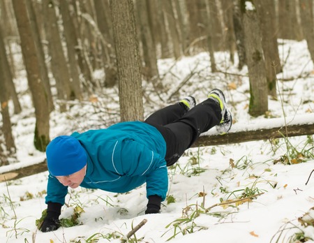 man performs exercise in the winter woods. Healthy lifestyle concept.の写真素材